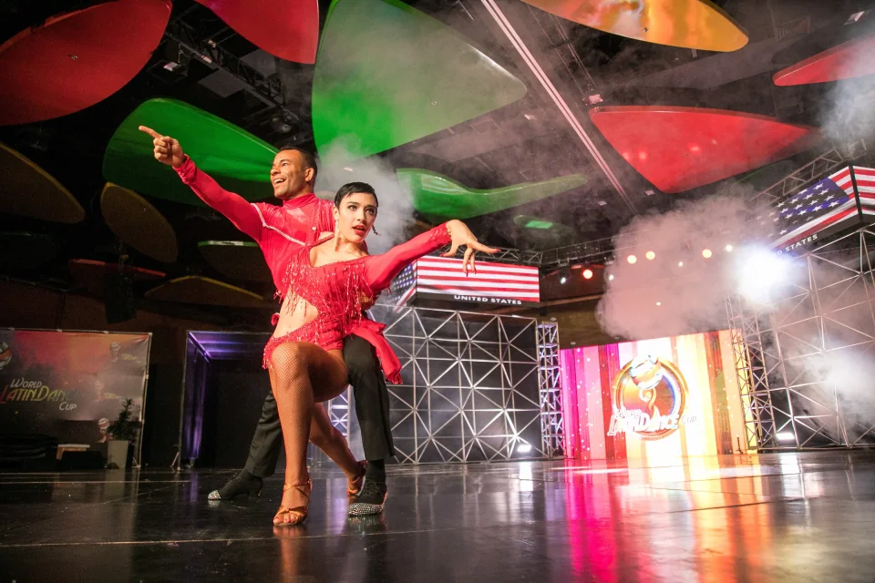 Takeshi Young and his partner performing in red costumes at the World Latin Dance Cup